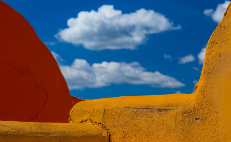 Blue sky and clouds framed by yellow and red walls.