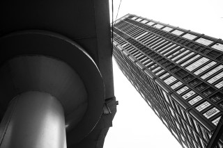 The underside of a cylindrical structure beside a tall modern building.